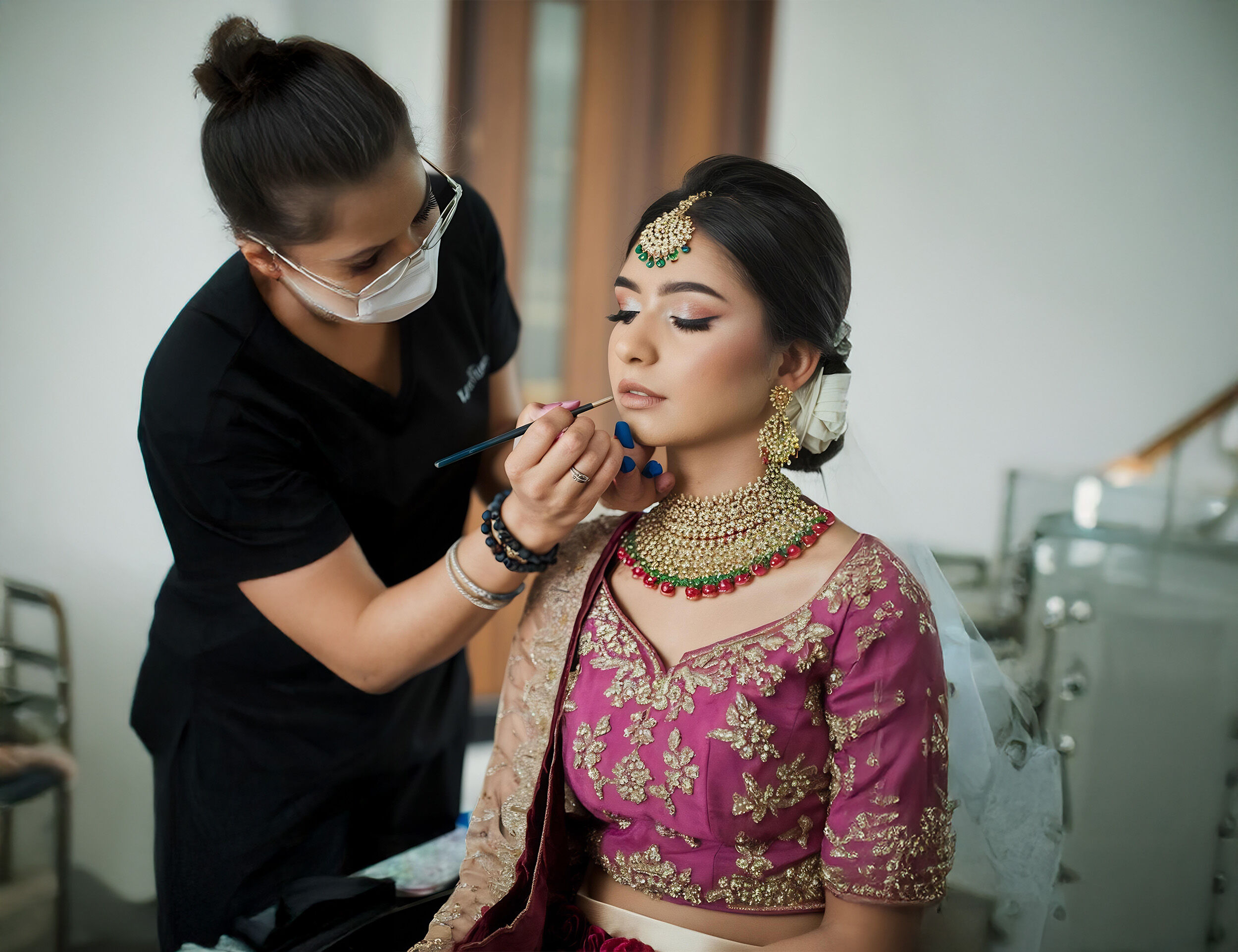 A stunning woman sitting in a salon chair as a makeup artist perfects her engagement look